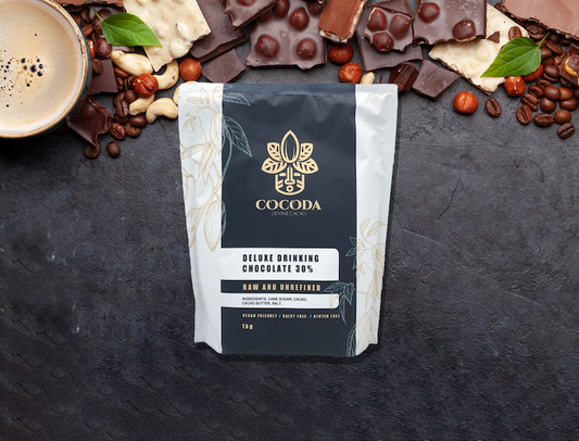Cocoda chocolate packaging with chocolate pieces, coffee beans, and a cup on a dark surface