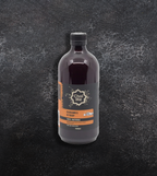 A bottle of Chai Me caramel coffee syrup on a textured dark background.