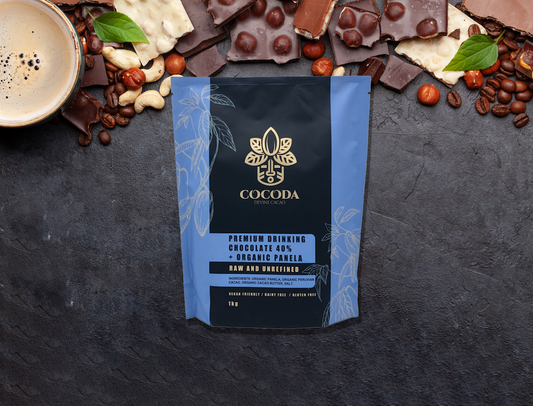 Cocoda premium drinking chocolate packaging surrounded by chocolate pieces and coffee beans on a dark surface